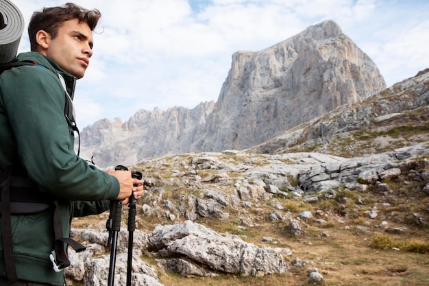 Male traveler hiking on mountains while having his essentials in a backpack