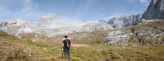 必需品をバックパックに入れて山をハイキングする男性旅行者