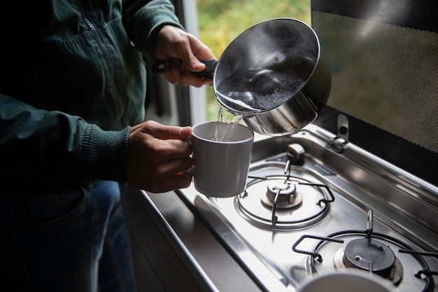 Male traveler making his coffee in a van