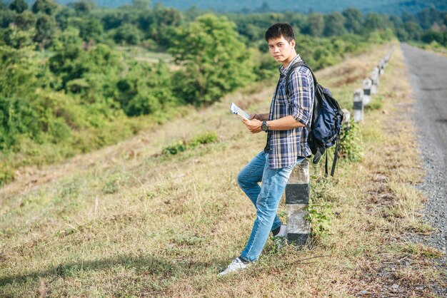 Male traveler with a backpack Holding a map and standing near to a kilometer.