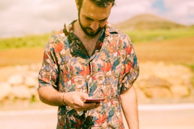 Мужчина печатает на экране мобильного телефона на открытом воздухе