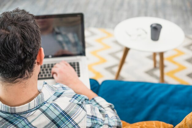 Male using laptop on sofa at home