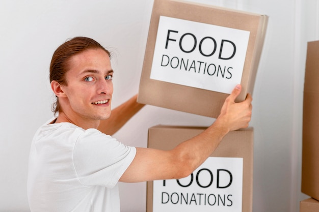 慈善団体向けの食料品が入った箱を扱う男性ボランティア