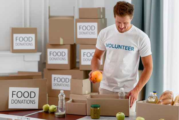男性ボランティアがチャリティーのための食物と一緒に箱を準備する
