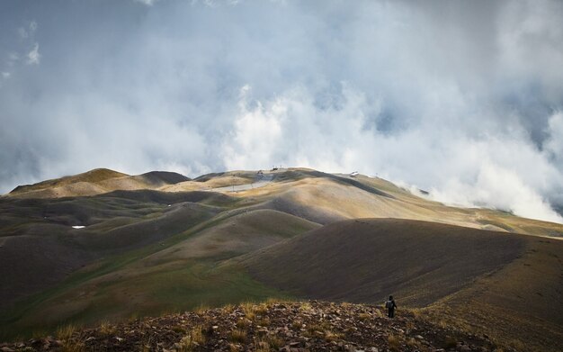 曇り空で山を歩く男性