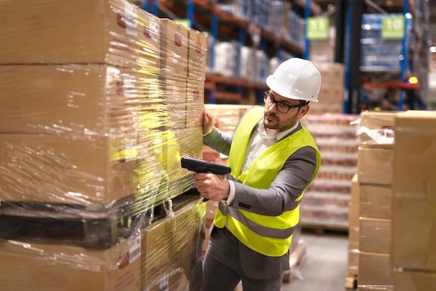 Male warehouse worker using bar code scanner to analyze newly arrived goods for further placement in storage department