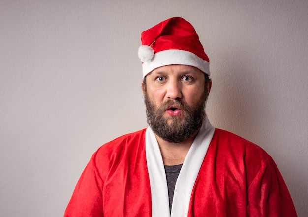 Male wearing a Santa Clause costume on grey