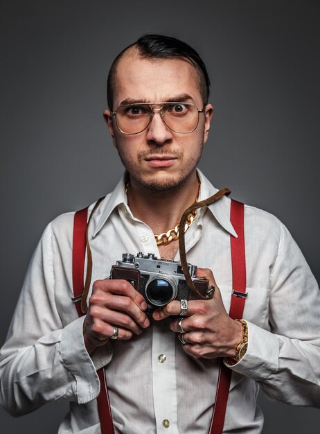 Male in white shirt holds photo camera. Isolated on grey.