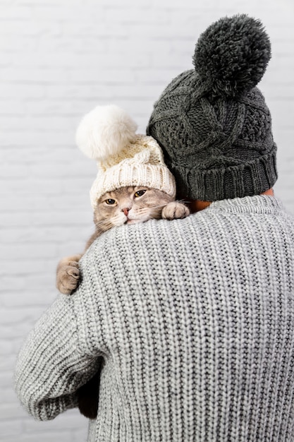 Free photo male with back holding cat with fur cap