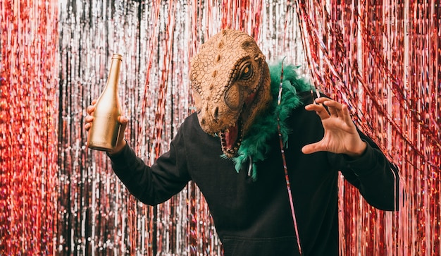 Мужчина с бутылкой шампанского в костюме динозавра