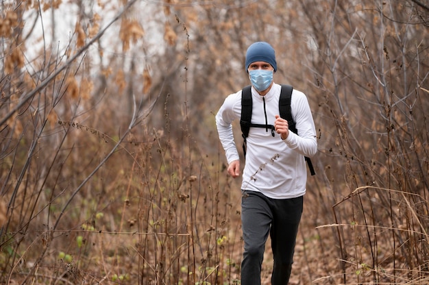 森の中を走っているフェイスマスクを持つ男性
