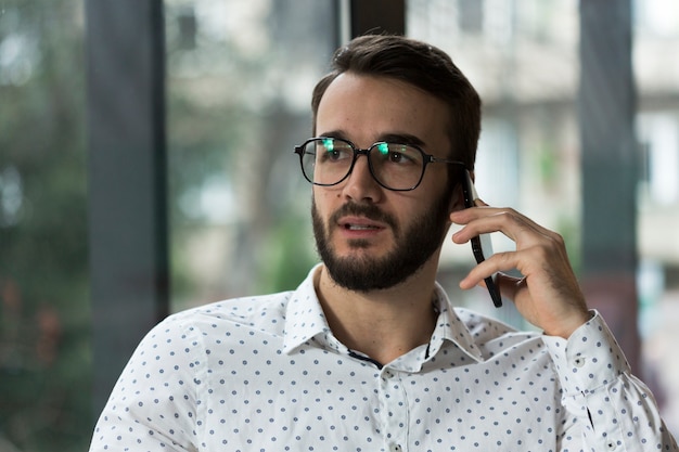 Male with glasses talking over phone