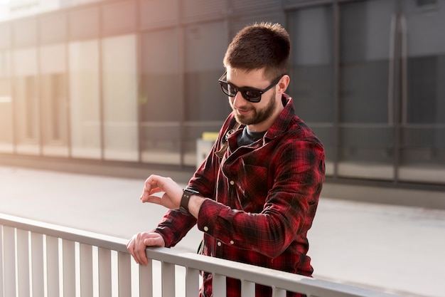 Foto gratuita maschio con occhiali da sole che controlla il tempo