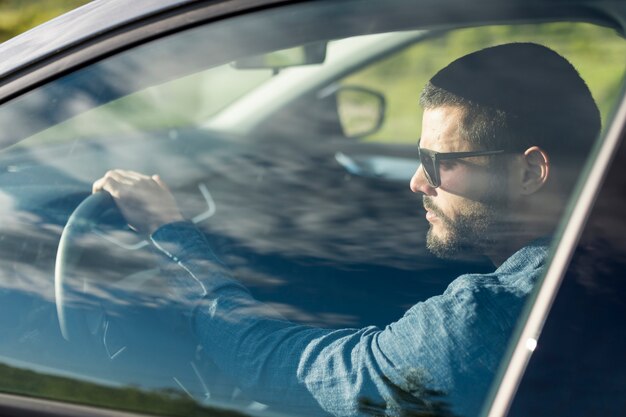 Male with sunglasses driving car