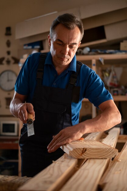 Foto gratuita falegname maschio nel suo negozio che lavora con strumenti e attrezzature