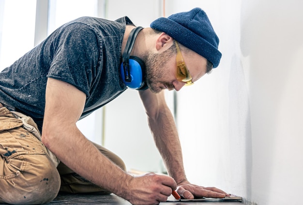 Foto gratuita un lavoratore di sesso maschile mette il pavimento in laminato sul pavimento