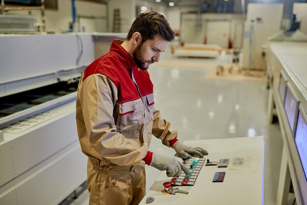 Male worker using automated machine while working at woodworking factory