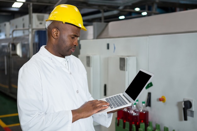 Male worker using laptop in juice factory