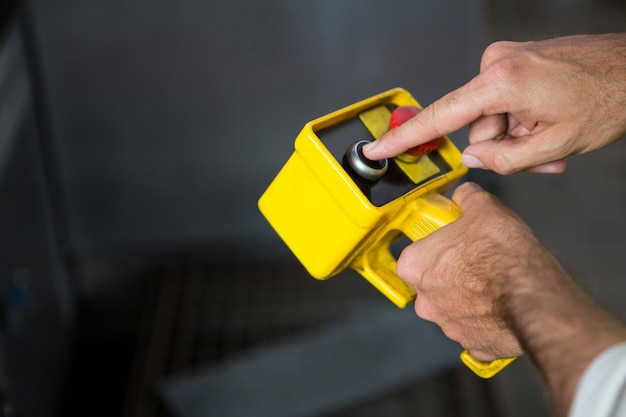 Lavoratore di sesso maschile utilizzando lo strumento giallo in fabbrica