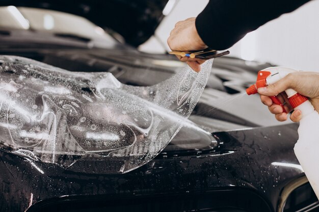 Male worker wrapping car with ptotective foil