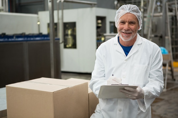 Male worker writing on notepad in cold drink factory