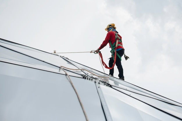 Male workers rope access height safety connecting with a knot safety harness, roof fall arrest and fall restraint anchor point systems ready to ascending, construction site oil tank dome
