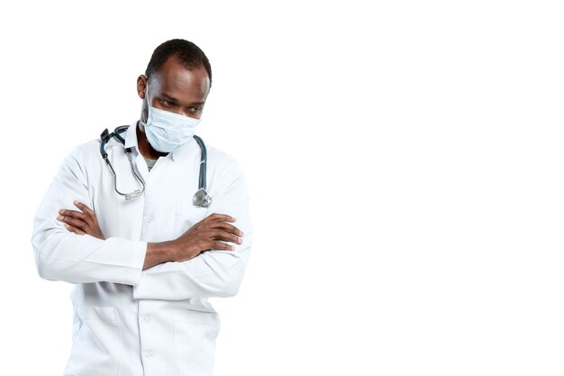 Молодой мужчина-врач со стетоскопом и маской, изолированной на белой стене