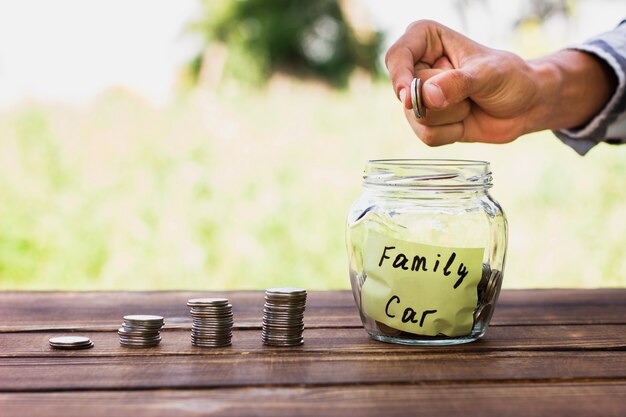 Man adding coins in jar with savings