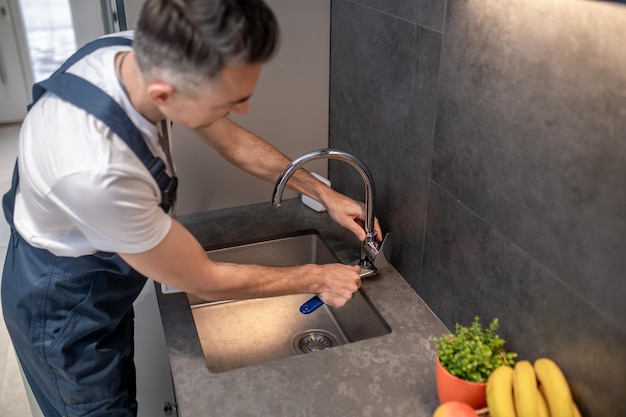 Man adjusting water tap with wrench