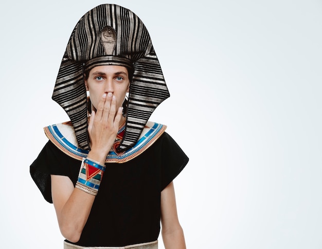 Free photo man in ancient egyptian costume being shocked coning mouth with hand on white