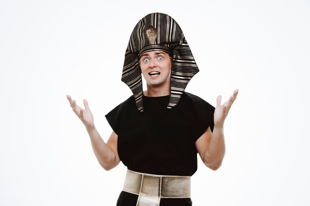 Man in ancient egyptian costume confused and excited raising arms on white