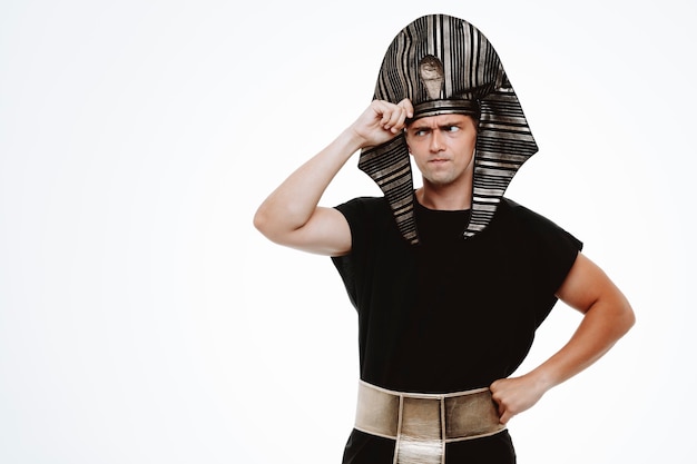 Man in ancient egyptian costume looking aside puzzled with hand on his head on white