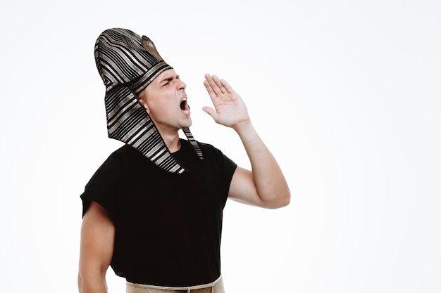 Man in ancient egyptian costume shouting loudly or calling someone with hand on mouth on white