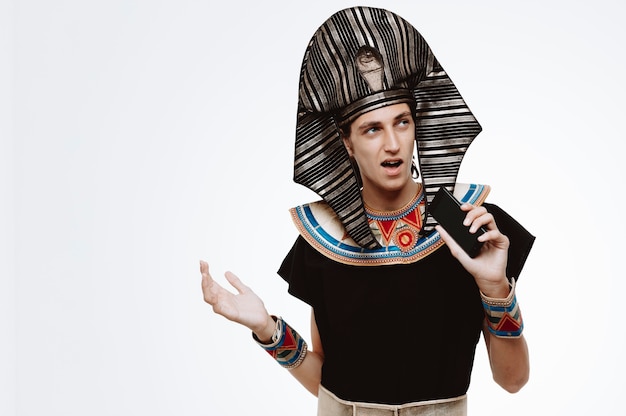 Free photo man in ancient egyptian costume singing a song using smartphone as microphone having fun on white