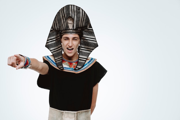 Free photo man in ancient egyptian costume smiling pointing with index finger to the side on white