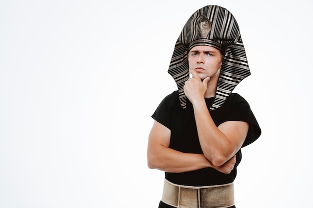 Man in ancient egyptian costume with pensive expression thinking with hand on his chin on white