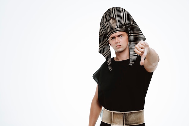 Man in ancient egyptian costume with serious face showing thumb down on white