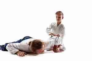 Бесплатное фото Мужчина и мальчик-подросток борются на тренировках по айкидо в школе боевых искусств