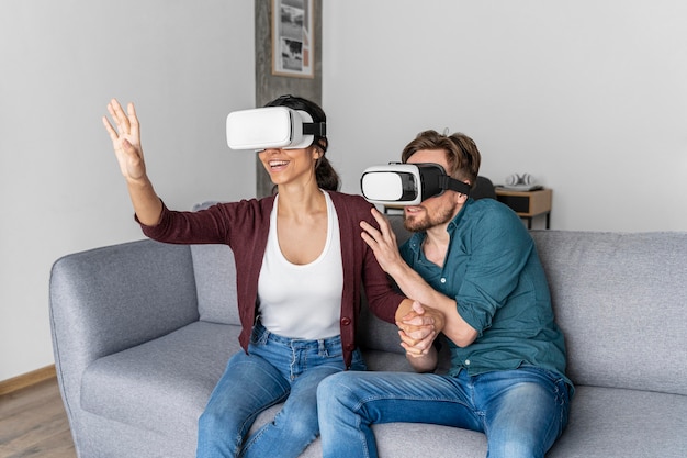Бесплатное фото Мужчина и женщина дома на диване с гарнитурой виртуальной реальности