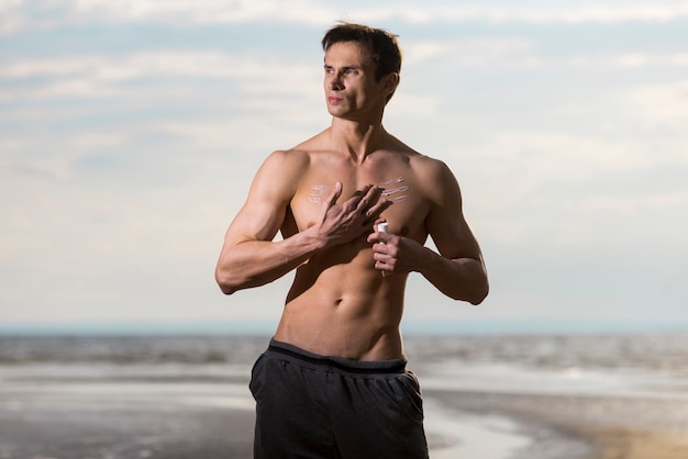 Man applying sunscreen lotion at seashore