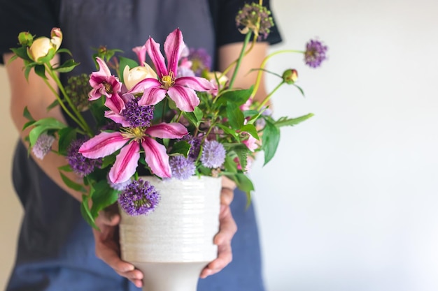 Free photo a man in an apron holds a vase of flowers closeup