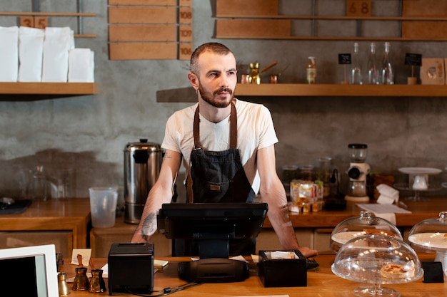 Man in apron posing at cash register