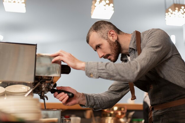 コーヒーマシンに取り組んでいるエプロンの男