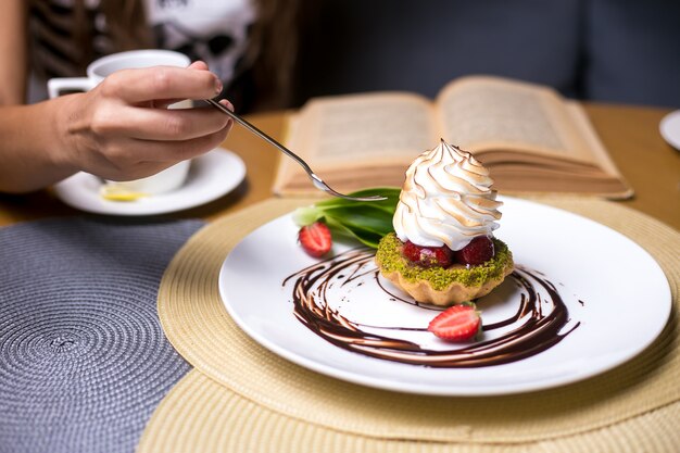 男はピスタチオのストロベリークリームチョコレートの側面図とタルトを食べるつもり