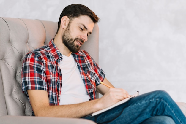 Man in armchair making notes