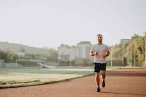 Free photo man athlete jogging at stadium in the morning