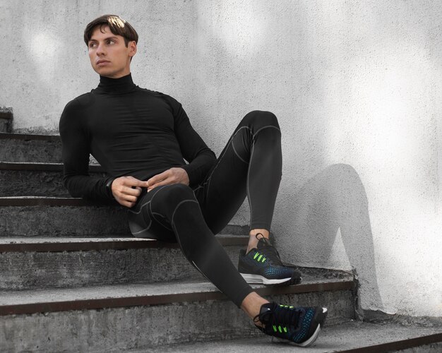 Man in athletic wear posing on stairs outdoors