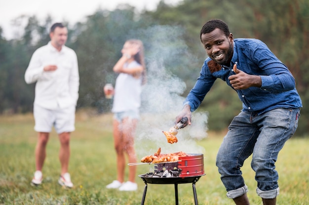 Foto gratuita uomo che partecipa al barbecue e che dà i pollici in su