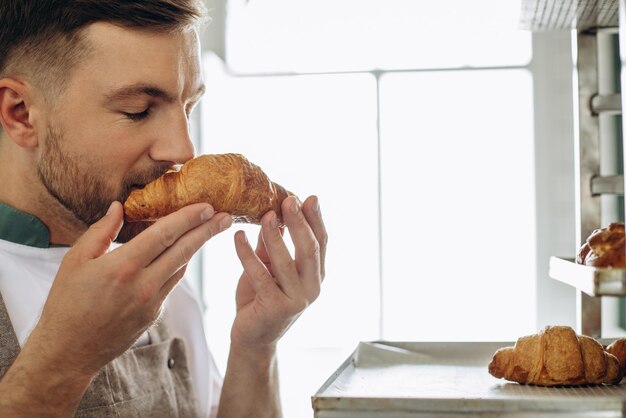 Man baker holding croissants at the bakehouse