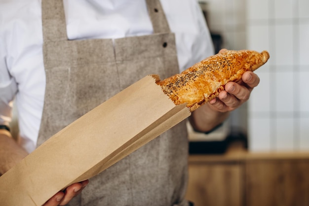 Man baker holding fresh bread in the paper bag